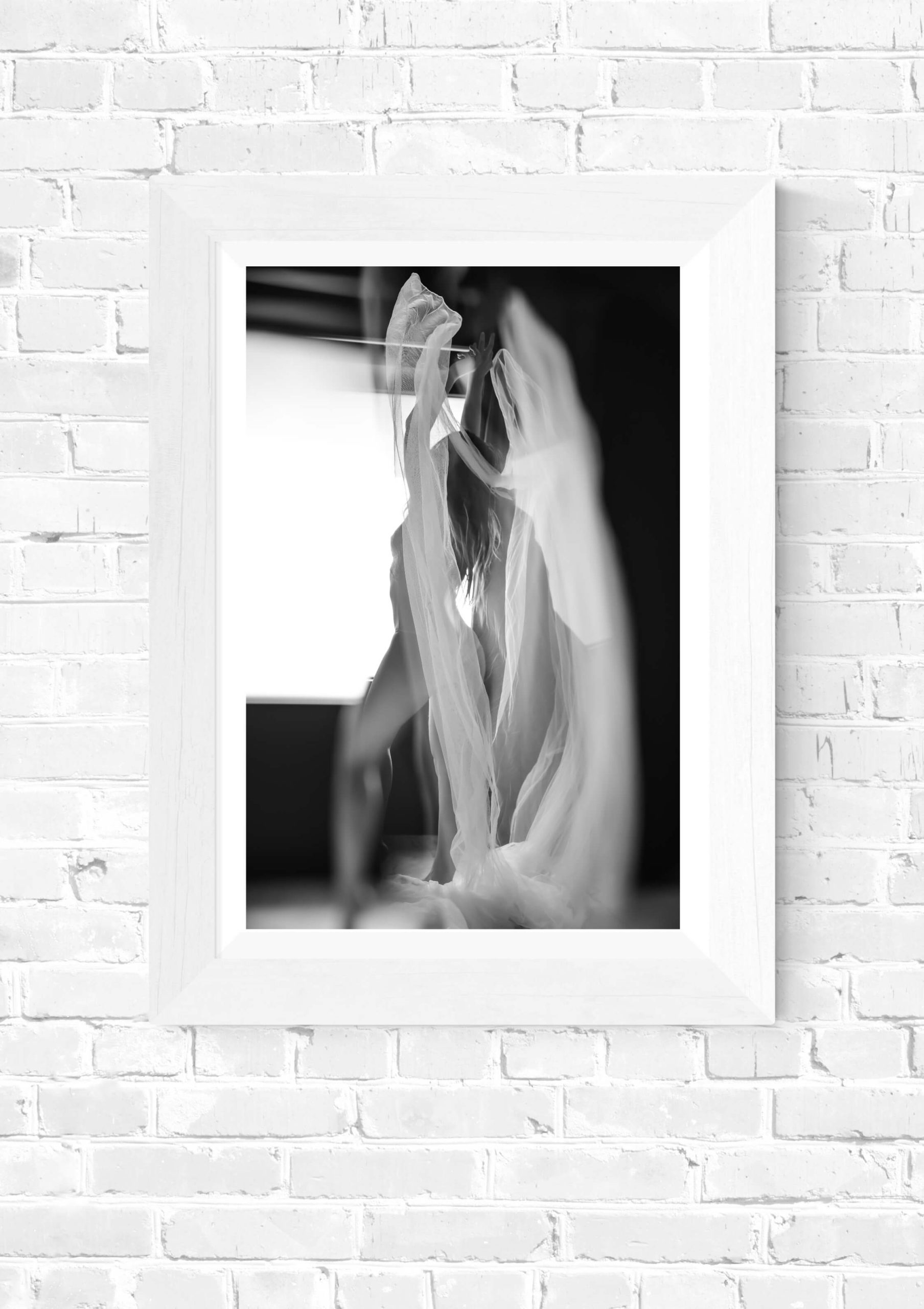 Boudoir wall art featuring a woman wrapped in soft fabric, partially in shadow.